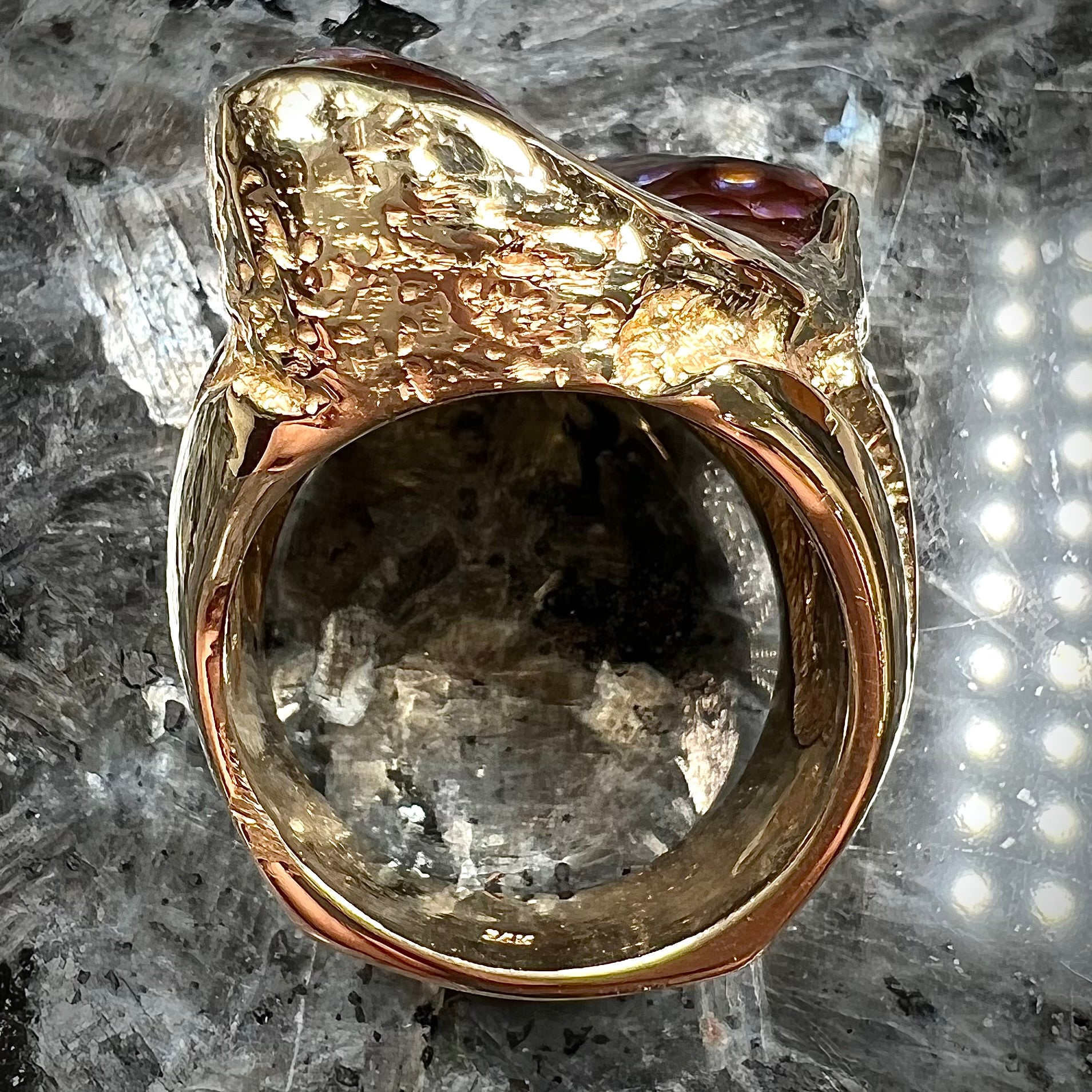 A men's Deer Creek fire agate solitaire ring cast in yellow gold.  The stone is predominantly purple.