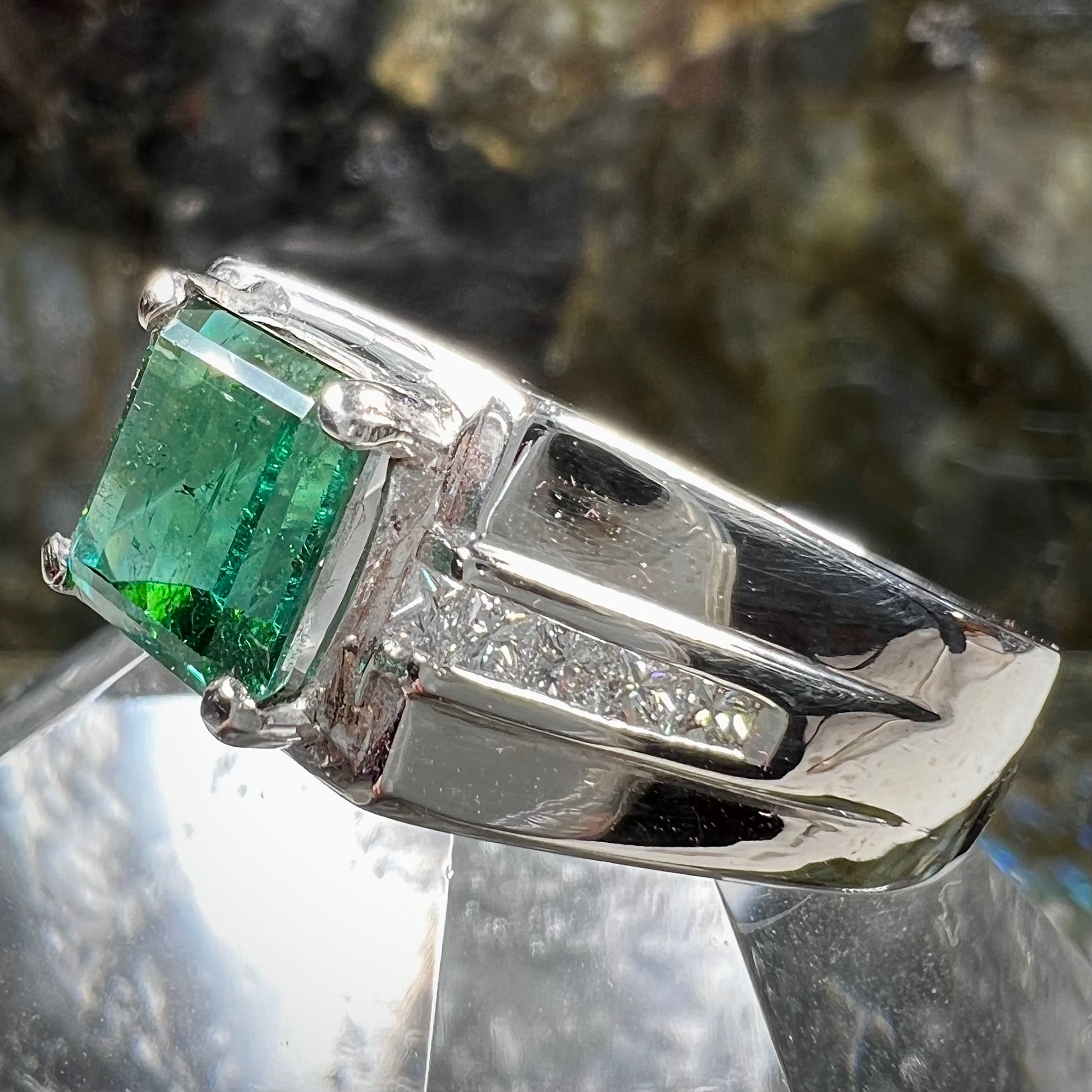 An 18k white gold green tourmaline and diamond men's ring.  The stones are princess cut.