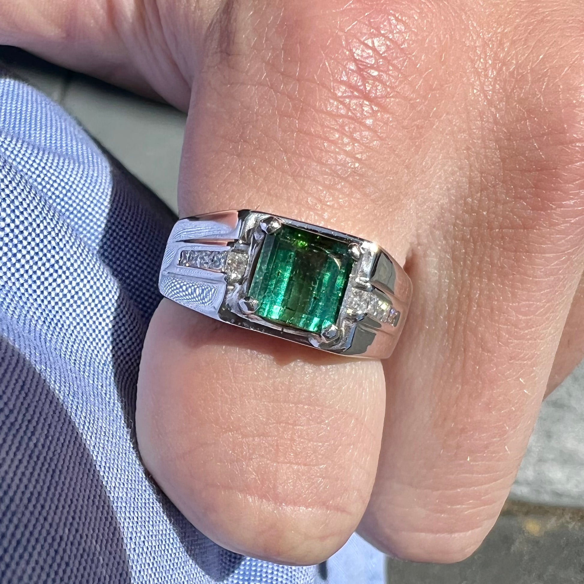 An 18k white gold green tourmaline and diamond men's ring.  The stones are princess cut.