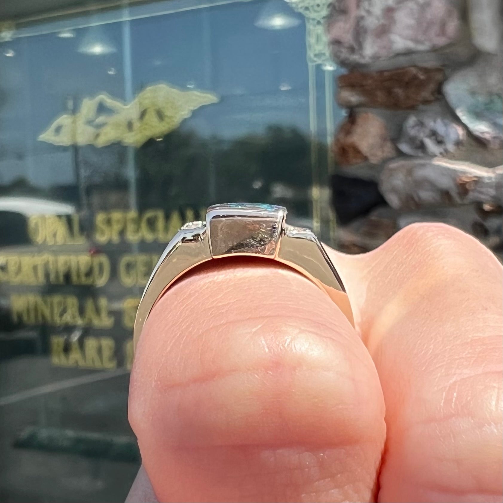 A men's gold boulder opal and diamond ring.  The opal shows blue and green colors.