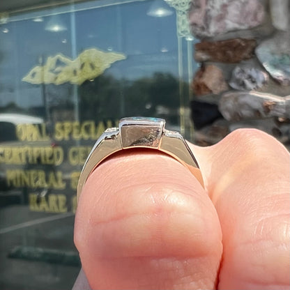A men's gold boulder opal and diamond ring.  The opal shows blue and green colors.
