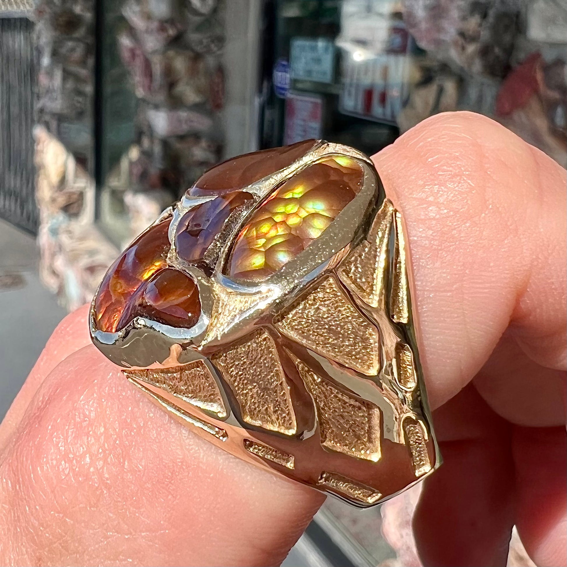 A yellow gold men's thug ring set with four fire agate stones resembling a spooky face.