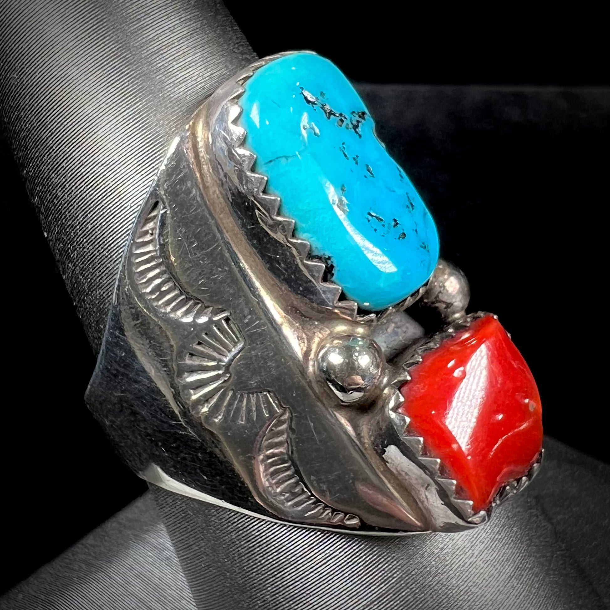 A men's sterling silver Navajo ring set with turquoise and red coral stones.
