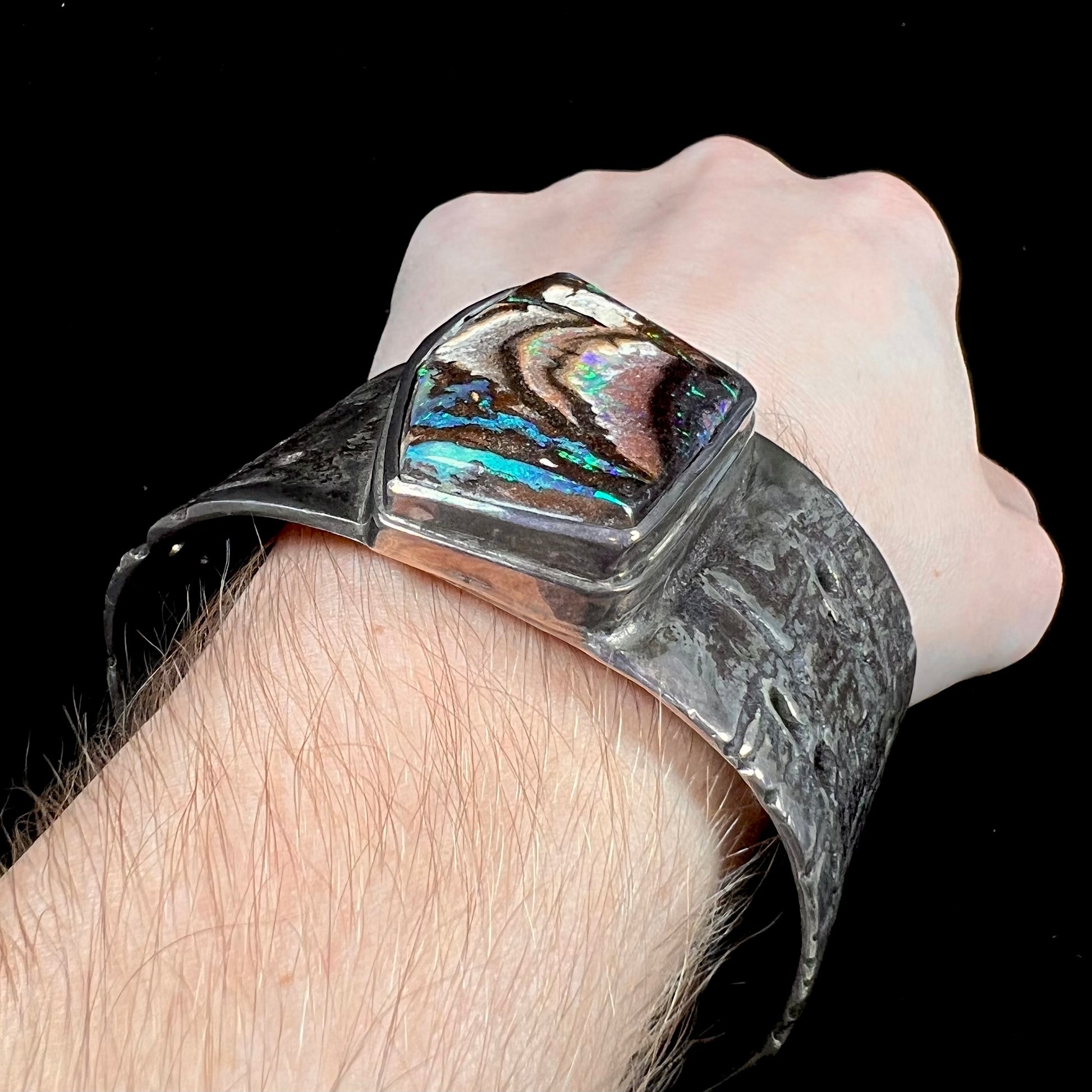 A men's sterling silver cuff bracelet set with an Australian Koroit boulder opal stone, handmade by Sam Yah.