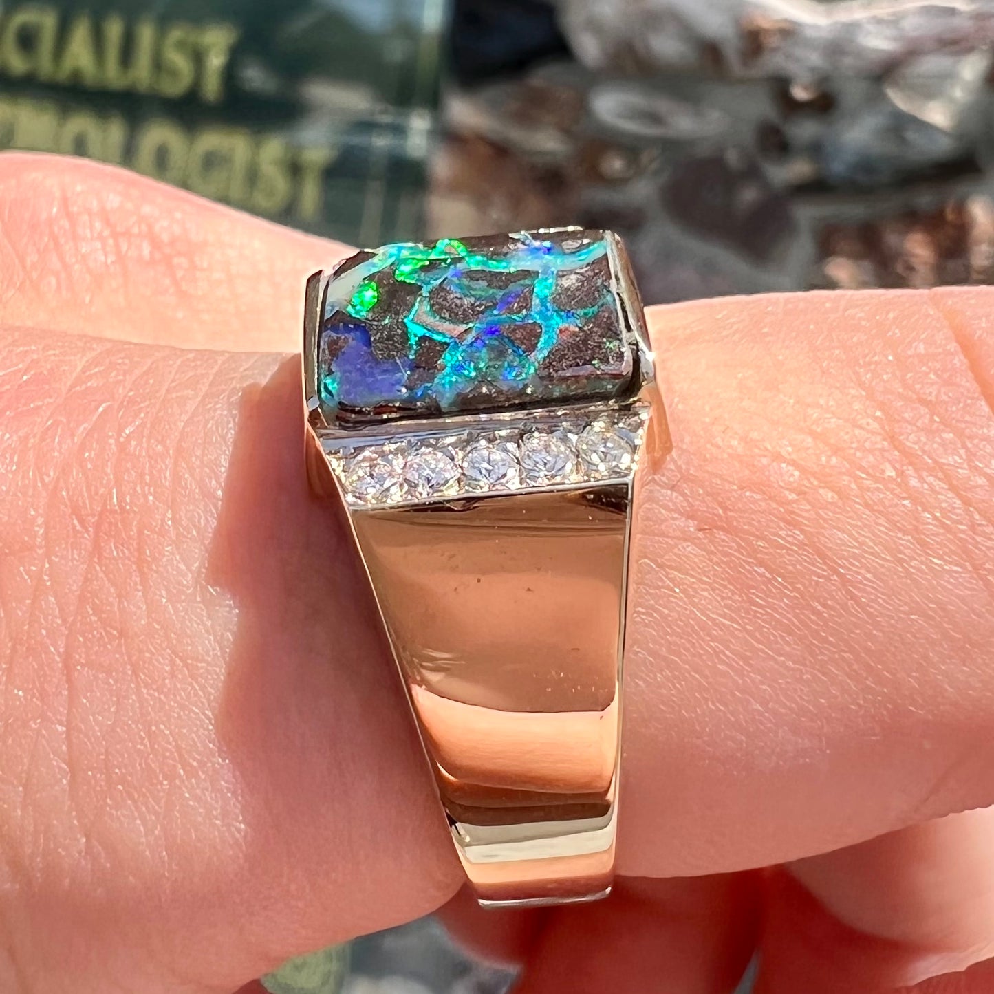 A men's gold boulder opal and diamond ring.  The opal shows blue and green colors.