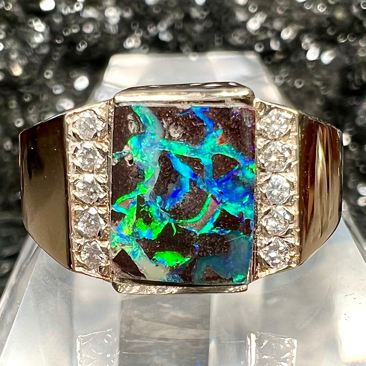 A men's gold boulder opal and diamond ring.  The opal shows blue and green colors.