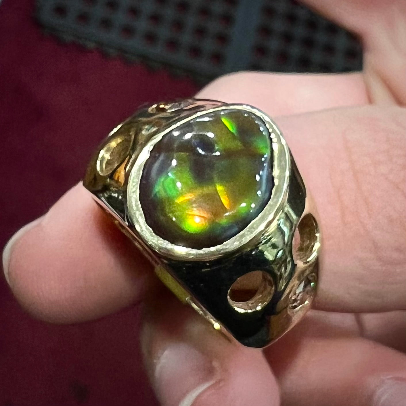 Men's rainbow fire agate ring set in yellow gold with champagne diamonds.  The ring style has holes.