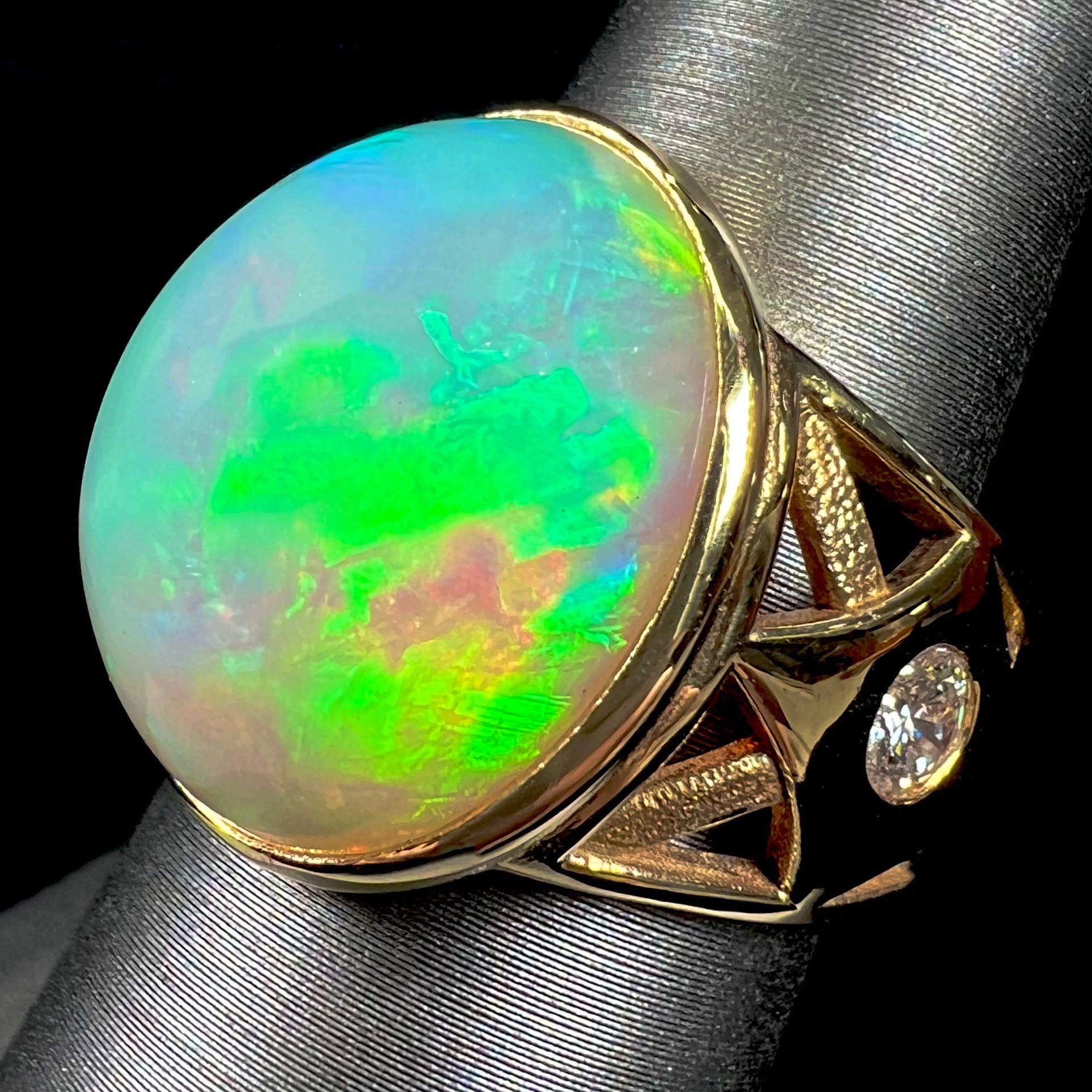 A custom yellow gold men's ring set with two diamonds and a large oval cabochon cut opal from Ethiopia, Africa.