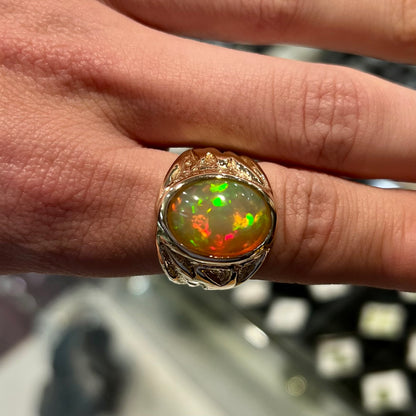 A solid yellow gold solitaire men's fire opal ring.  The stone is an orange oval cabochon cut.