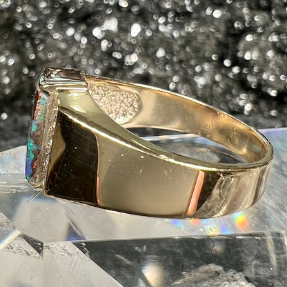 A men's gold boulder opal and diamond ring.  The opal shows blue and green colors.