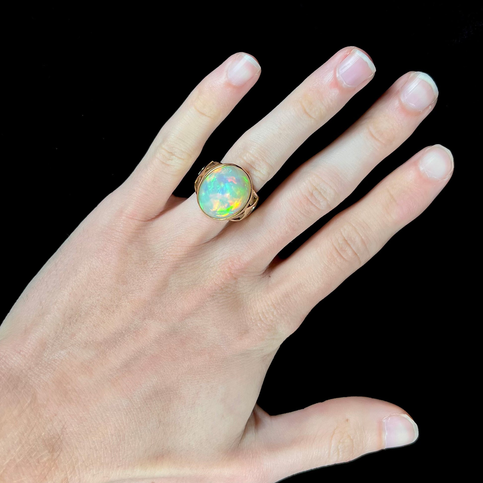 A custom yellow gold men's ring set with two diamonds and a large oval cabochon cut opal from Ethiopia, Africa.