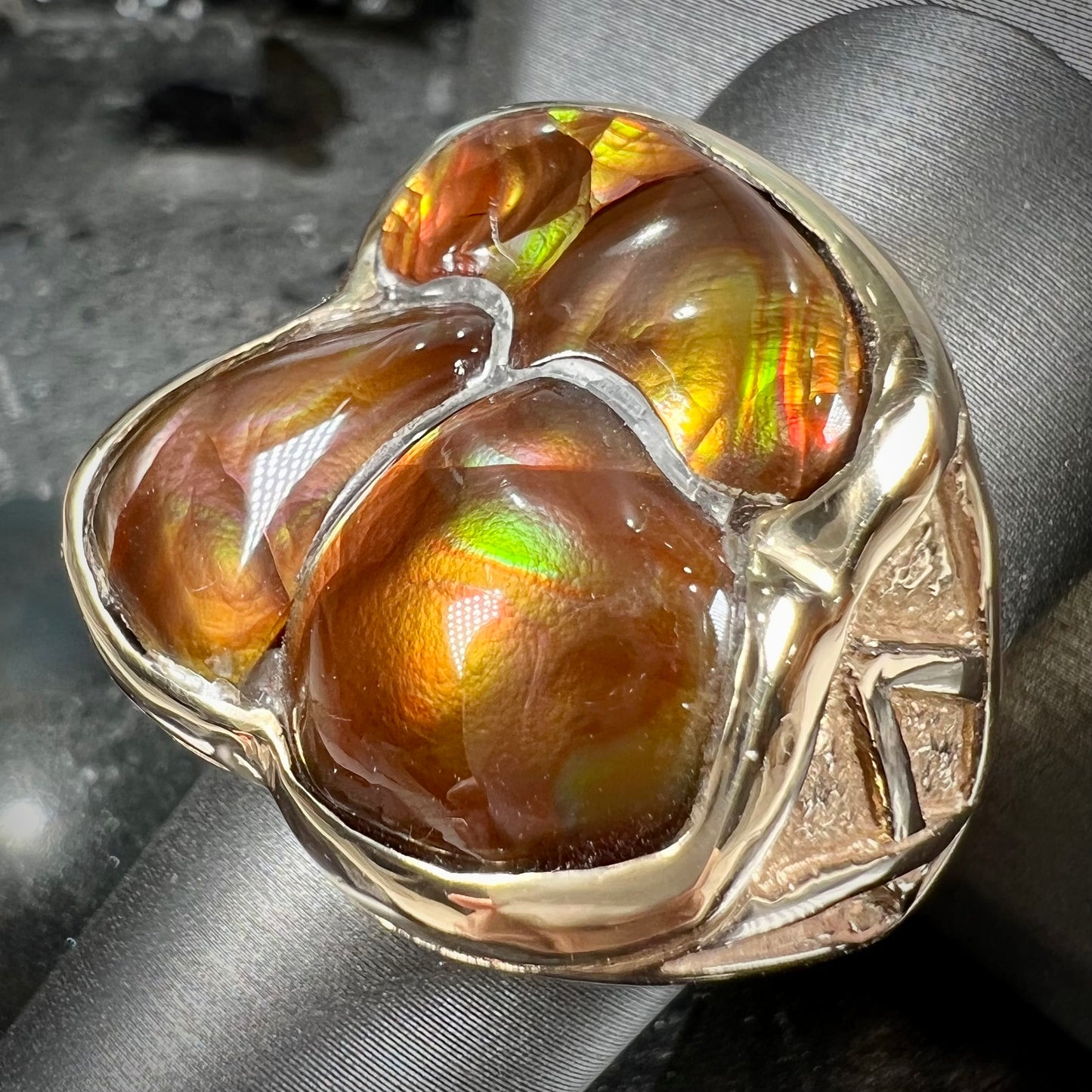 A men's yellow gold ring inlaid with three freeform cut fire agate stones.
