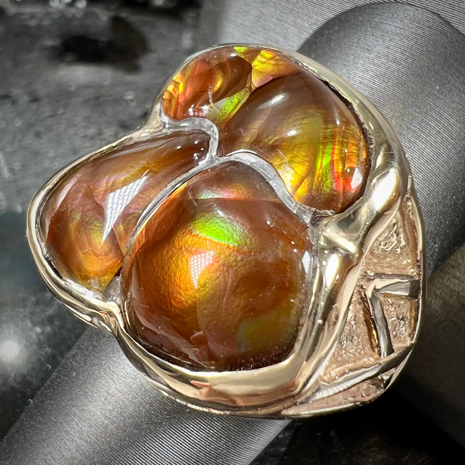 A men's yellow gold ring inlaid with three freeform cut fire agate stones.