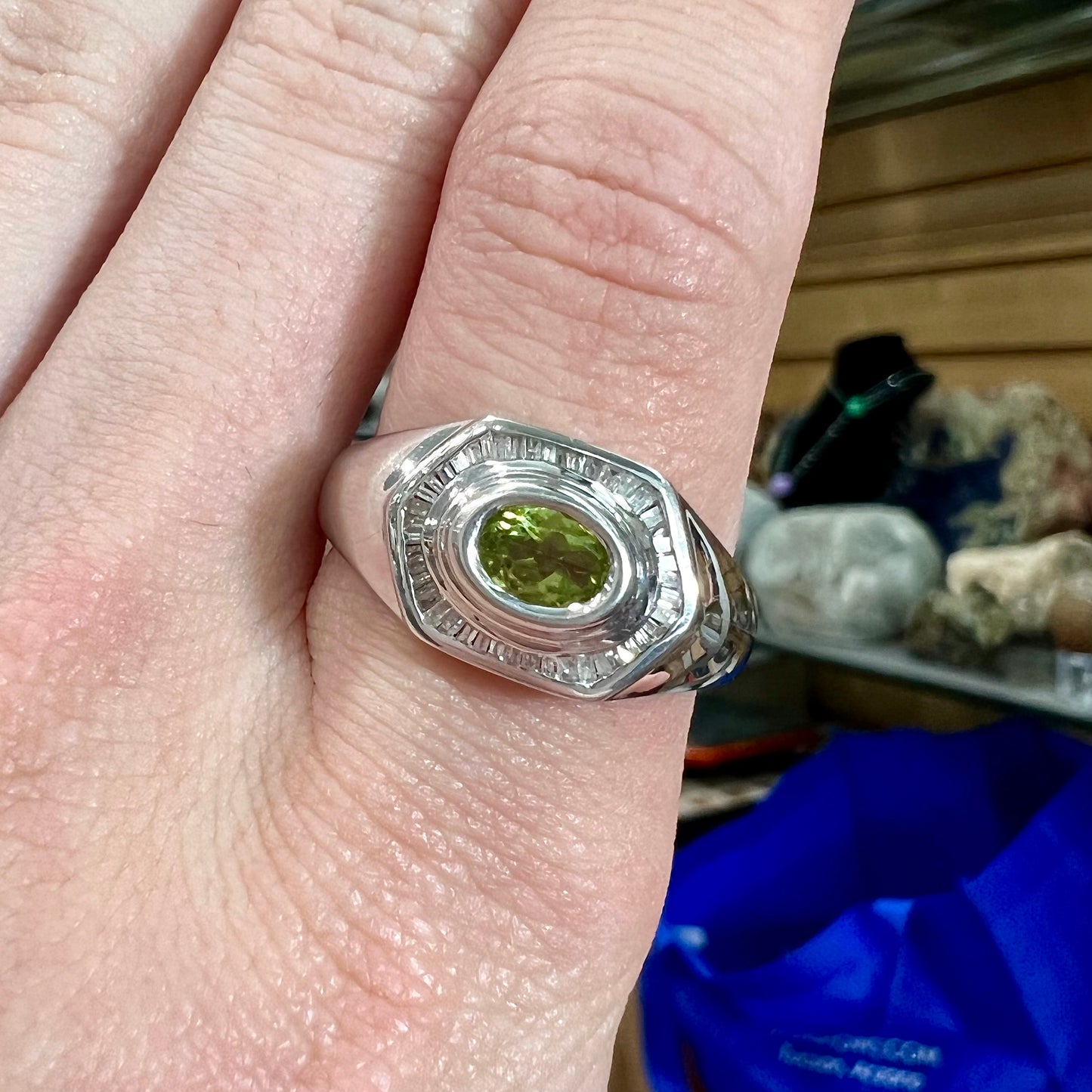 A sterling silver men's ring set with green peridot surrounded by baguette cut diamonds.