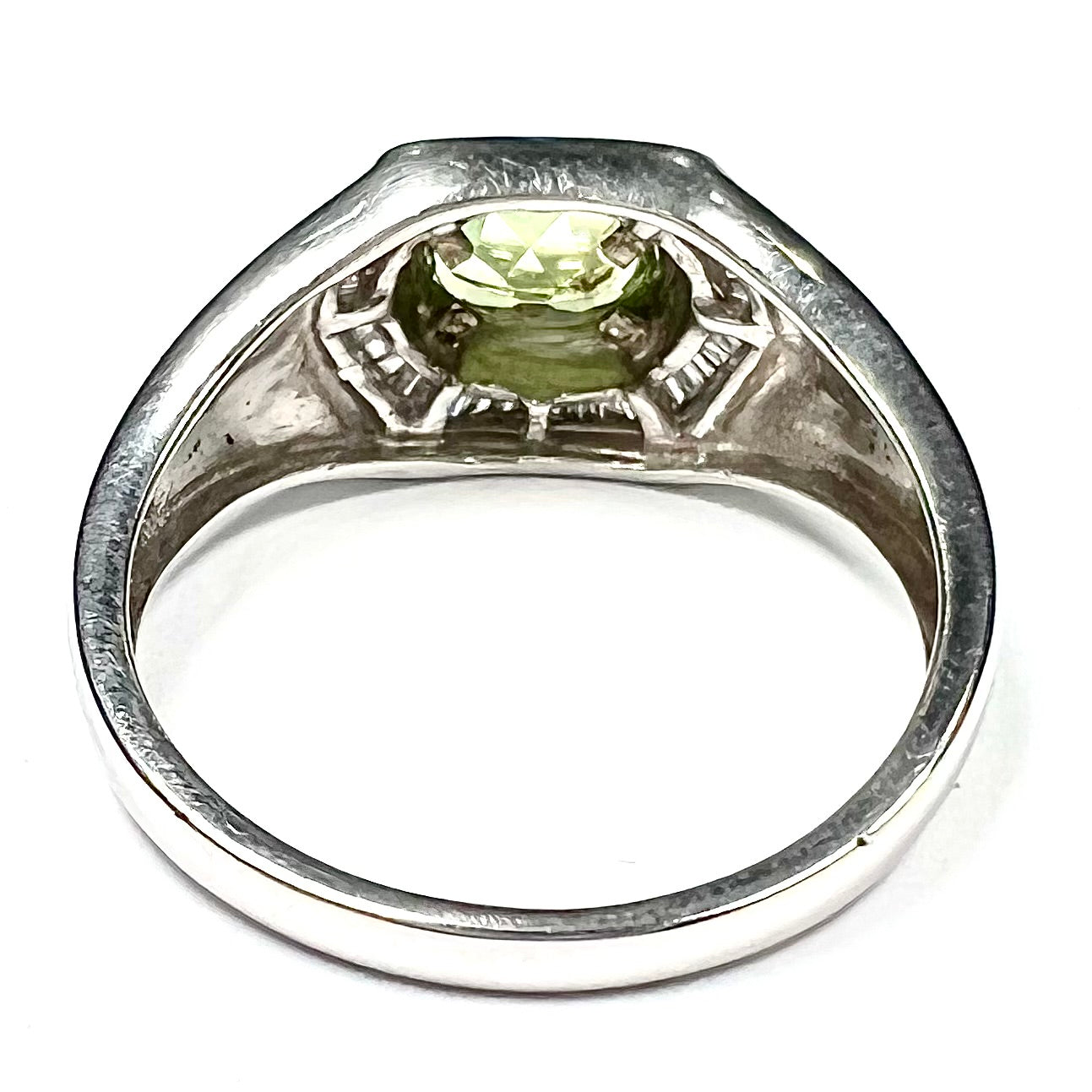 A sterling silver men's ring set with green peridot surrounded by baguette cut diamonds.