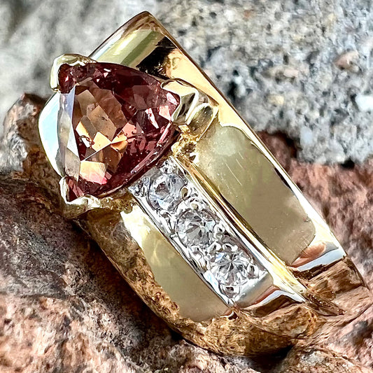 A men's gold pink tourmaline ring.  Set next to the trillion cut tourmaline is a row of three round white sapphires.