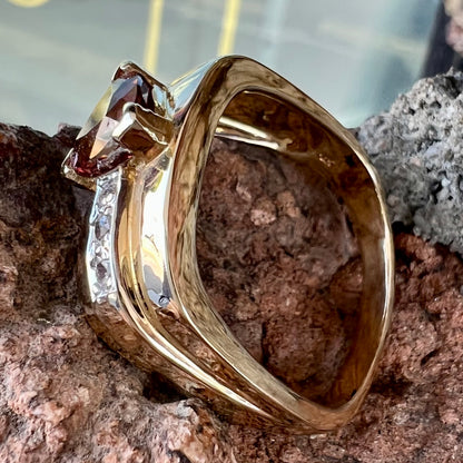 A men's gold pink tourmaline ring.  Set next to the trillion cut tourmaline is a row of three round white sapphires.
