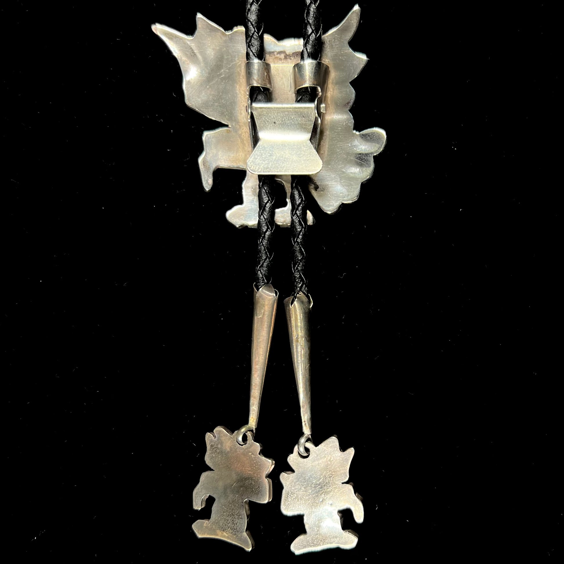 A sterling silver Zuni Indian-made bolo tie featuring the motif of three flying eagles inlaid with natural stones.