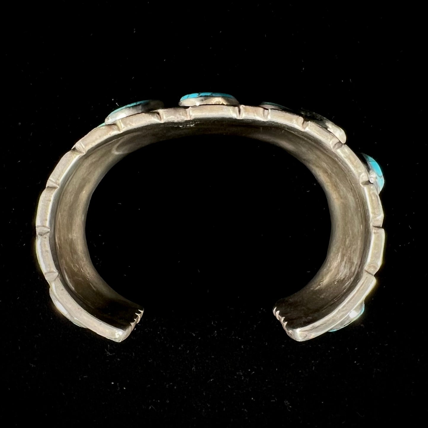 A men's sterling silver cuff bracelet bezel set with natural and synthetic turquoise stones.