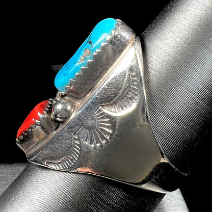 A men's sterling silver Navajo ring set with turquoise and red coral stones.