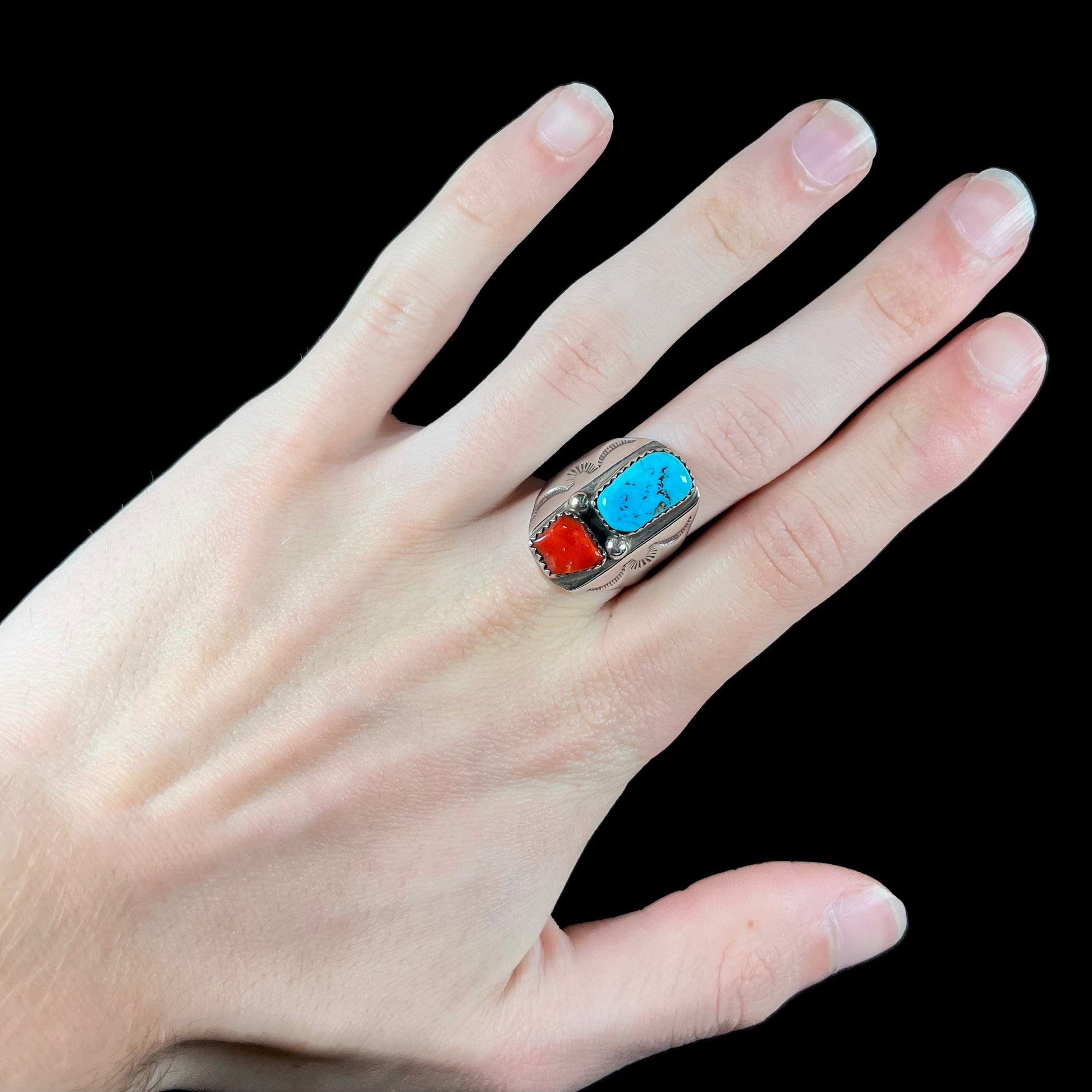 A men's sterling silver Navajo ring set with turquoise and red coral stones.