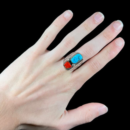 A men's sterling silver Navajo ring set with turquoise and red coral stones.