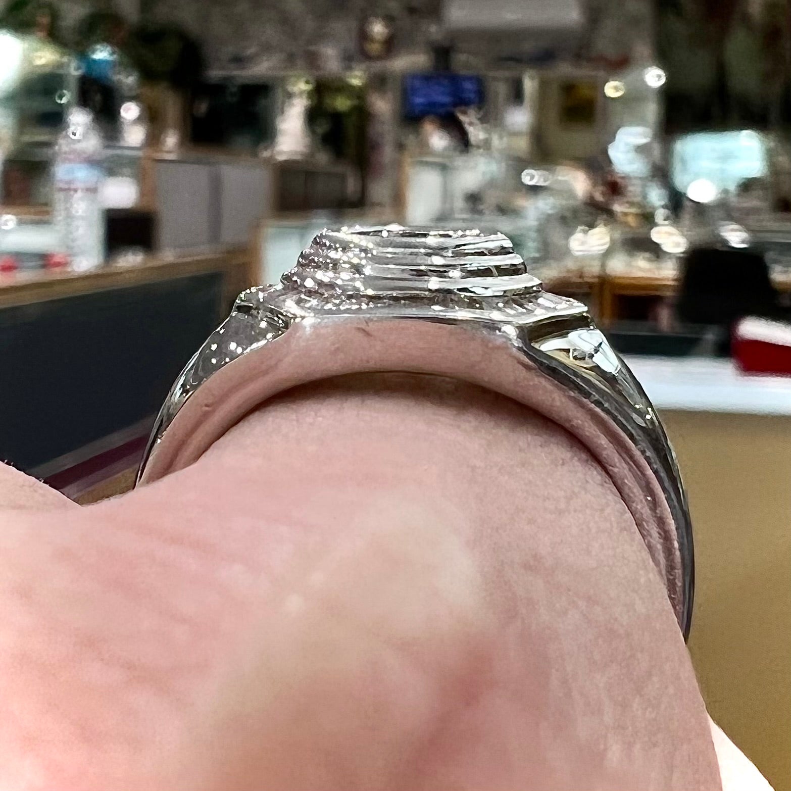 A sterling silver men's ring set with green peridot surrounded by baguette cut diamonds.