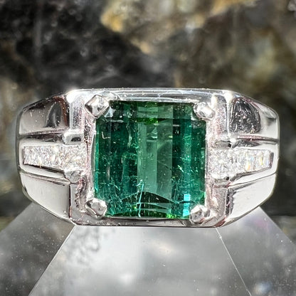 An 18k white gold green tourmaline and diamond men's ring.  The stones are princess cut.