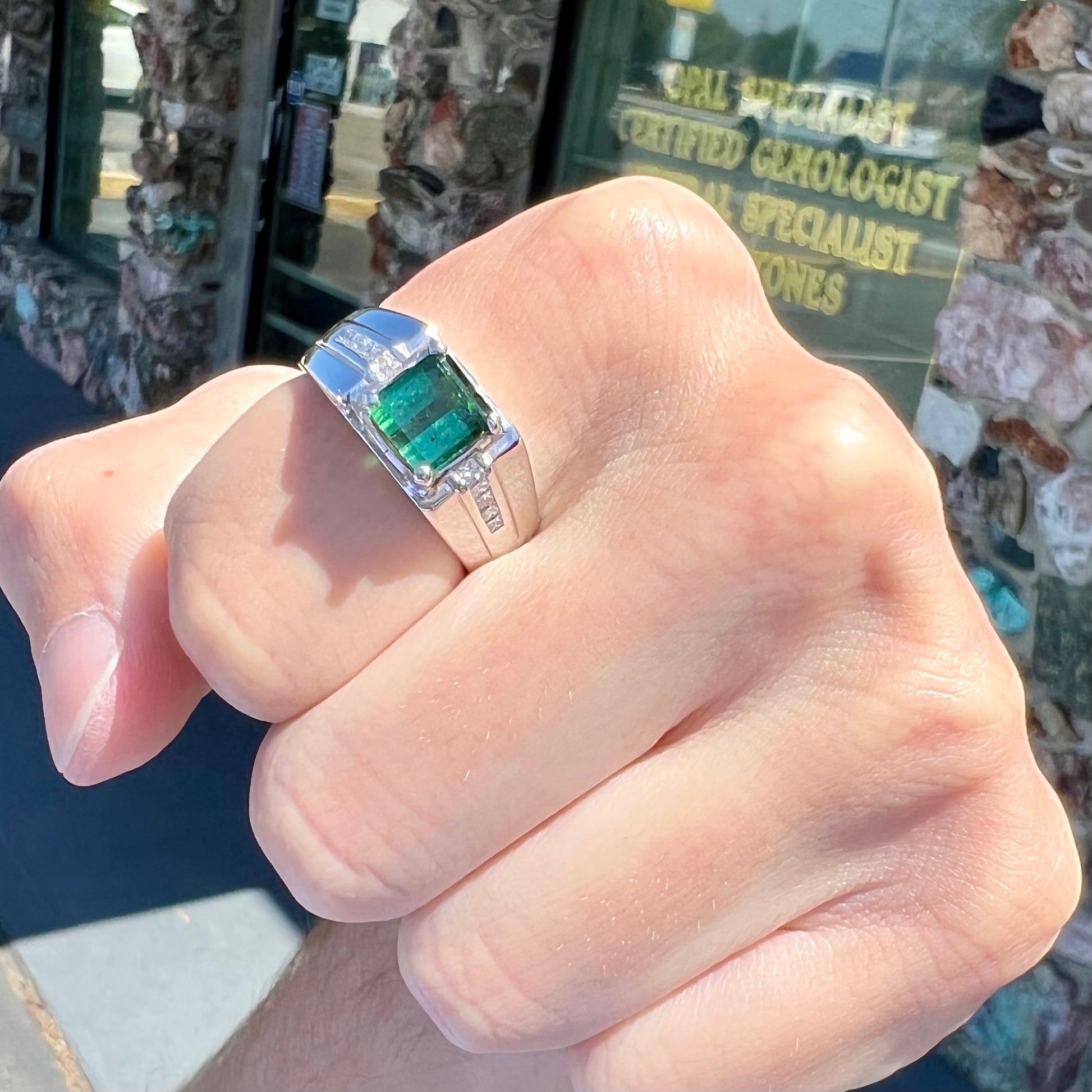 An 18k white gold green tourmaline and diamond men's ring.  The stones are princess cut.
