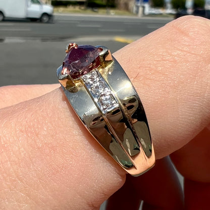 A men's gold pink tourmaline ring.  Set next to the trillion cut tourmaline is a row of three round white sapphires.