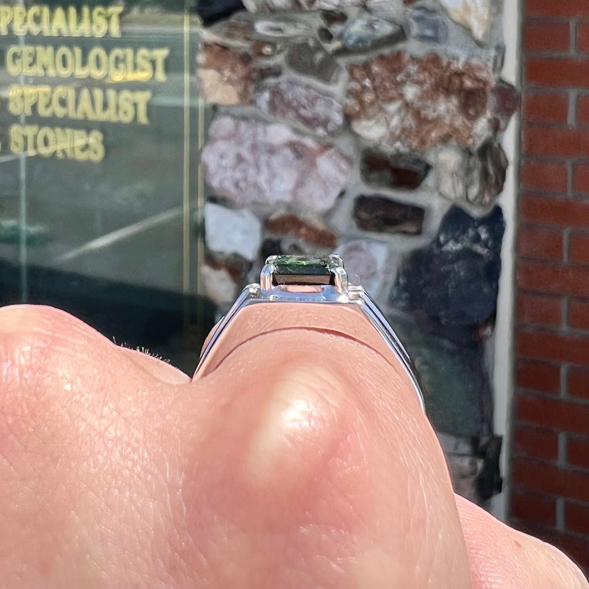 An 18k white gold green tourmaline and diamond men's ring.  The stones are princess cut.