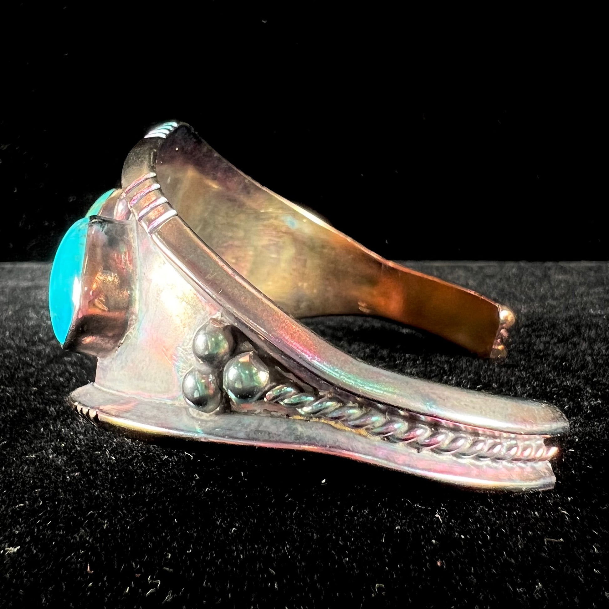 A men's Navajo three stone turquoise cuff bracelet handmade by artist, Dean Brown.  The silver has an iridescent purple patina.