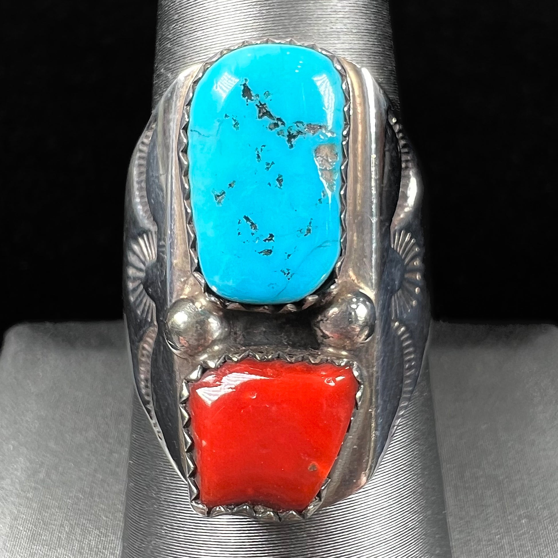A men's sterling silver Navajo ring set with turquoise and red coral stones.