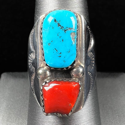 A men's sterling silver Navajo ring set with turquoise and red coral stones.