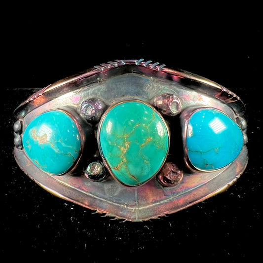 A men's Navajo three stone turquoise cuff bracelet handmade by artist, Dean Brown.  The silver has an iridescent purple patina.