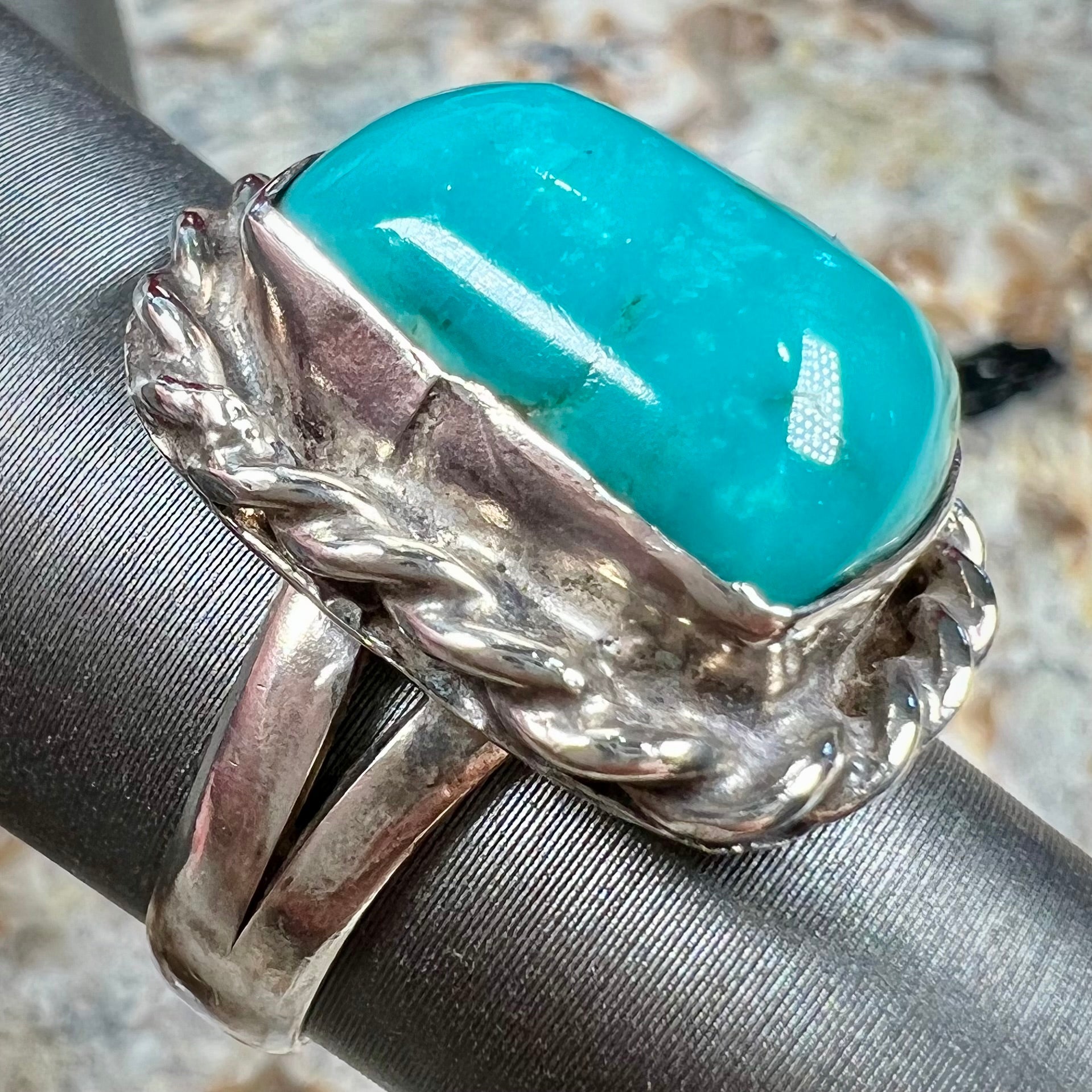 A sterling silver turquoise split shank ring.  There is a handmade silver rope around the turquoise.