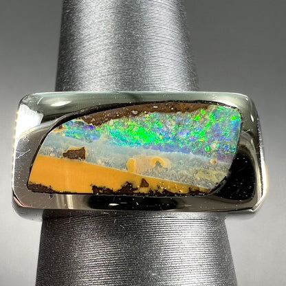 A white gold flush set boulder opal solitaire ring.  The style is unisex.