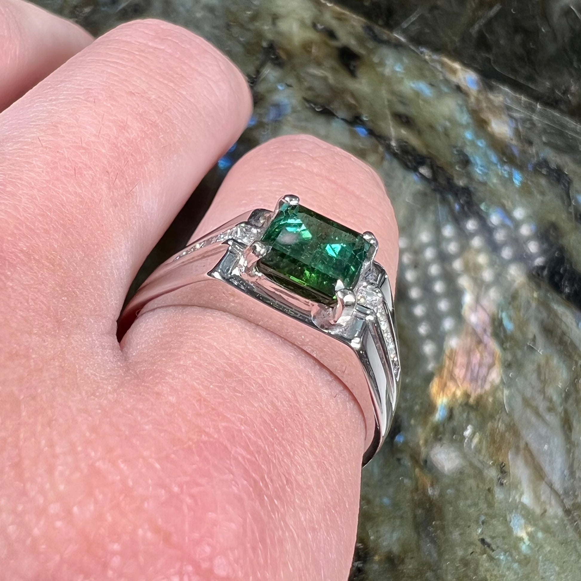 An 18k white gold green tourmaline and diamond men's ring.  The stones are princess cut.
