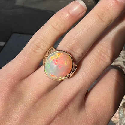 A custom yellow gold men's ring set with two diamonds and a large oval cabochon cut opal from Ethiopia, Africa.