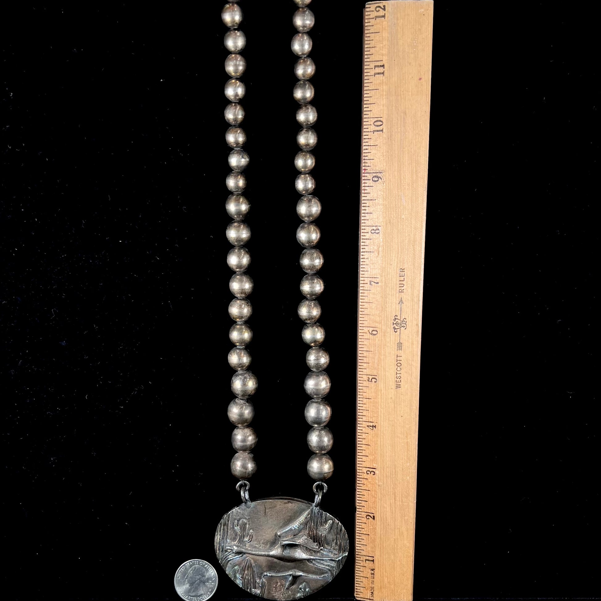 A handmade sterling silver bead necklace with a rainbow patinaed medallion that features 3D cast flamingos flying through a cactus desert.
