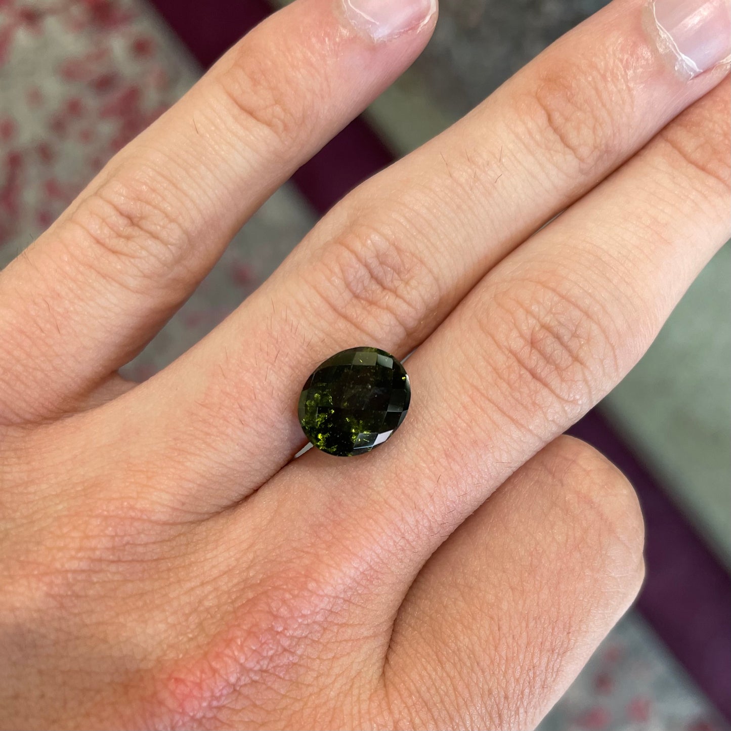 A faceted oval checkerboard cut moldavite gemstone that weighs 4.14 carats.