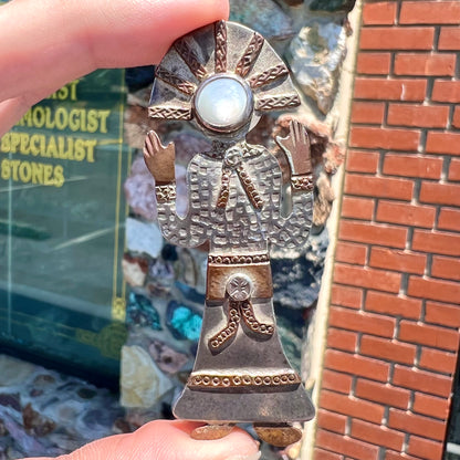 A handmade Navajo style silver pendant with copper highlights shaped like a Navajo Indian shaman.  There is a mother of pearl set as the shaman's face.