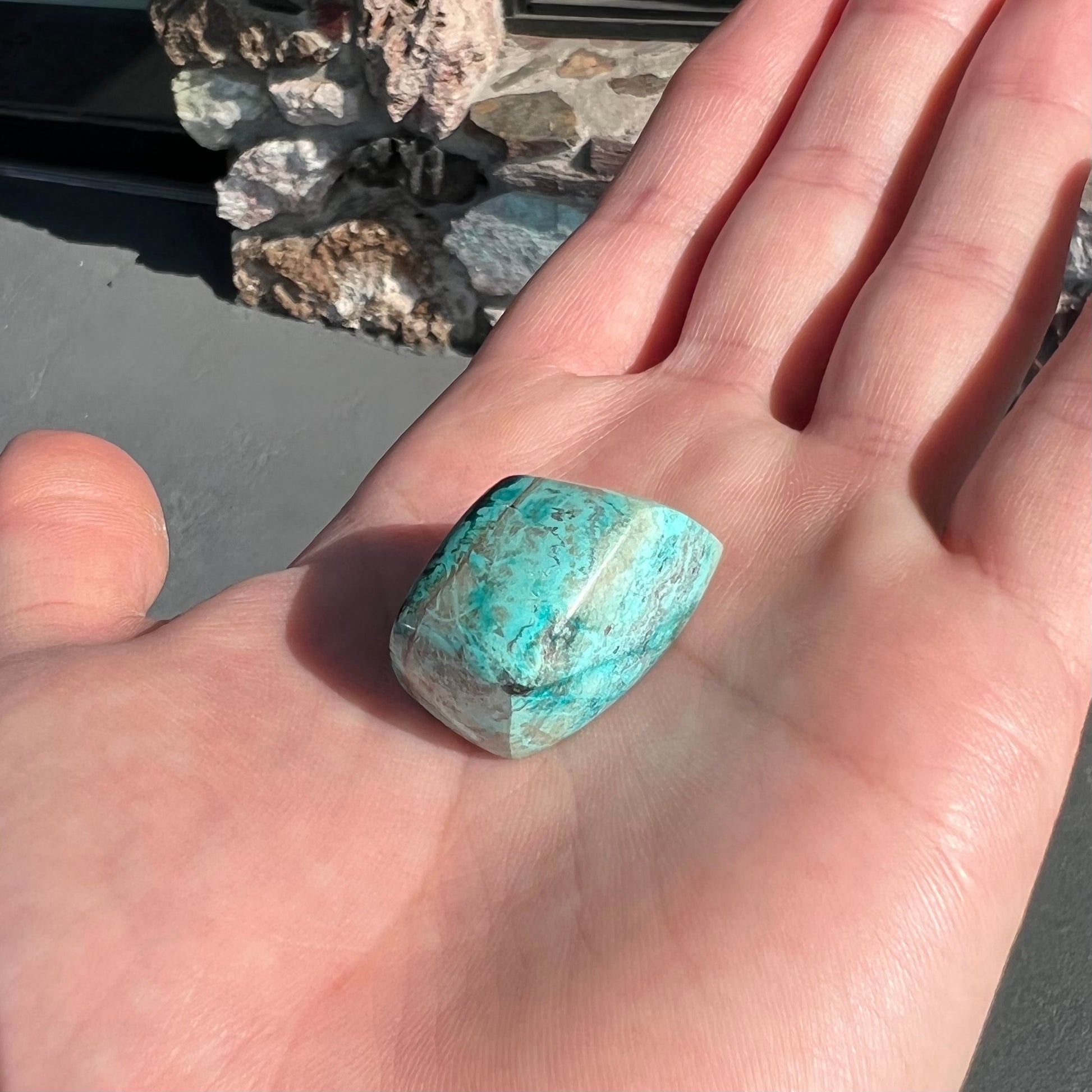 A loose, polished turquoise specimen with azurite inclusions.