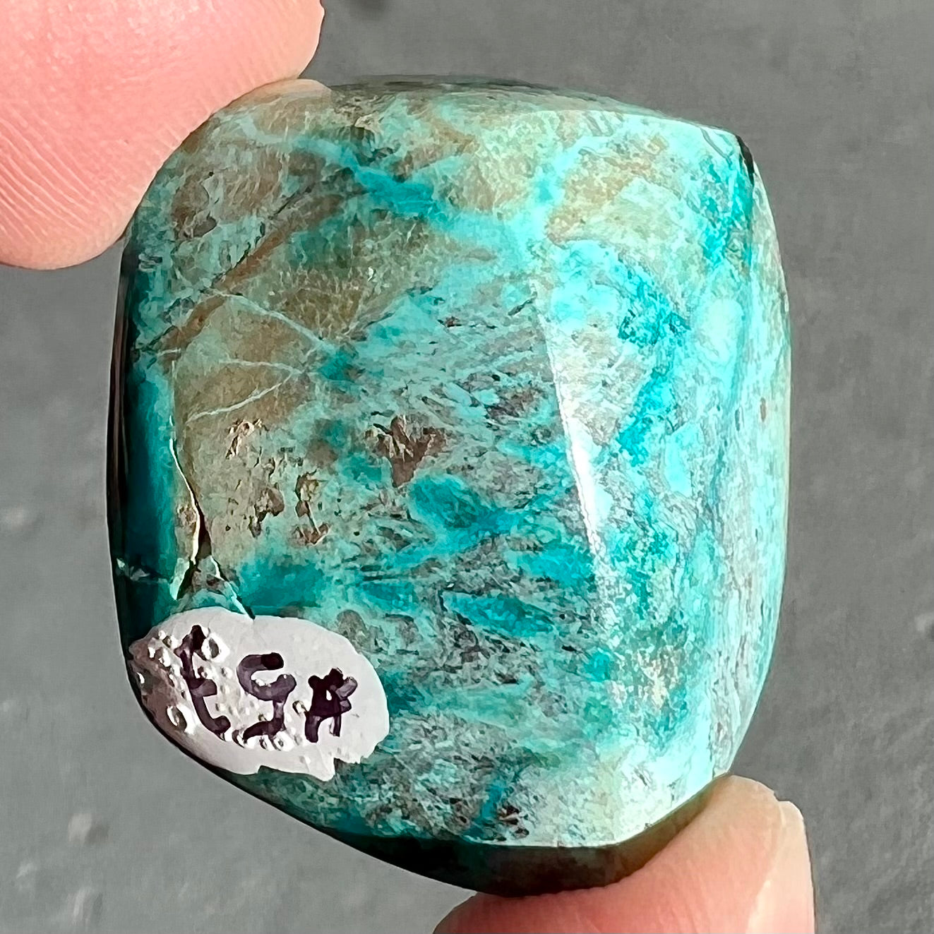 A loose, polished turquoise specimen with azurite inclusions.