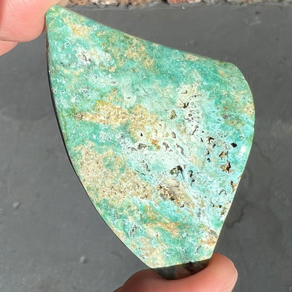 A triangular cut polished green turquoise stone from Morenci, Arizona.