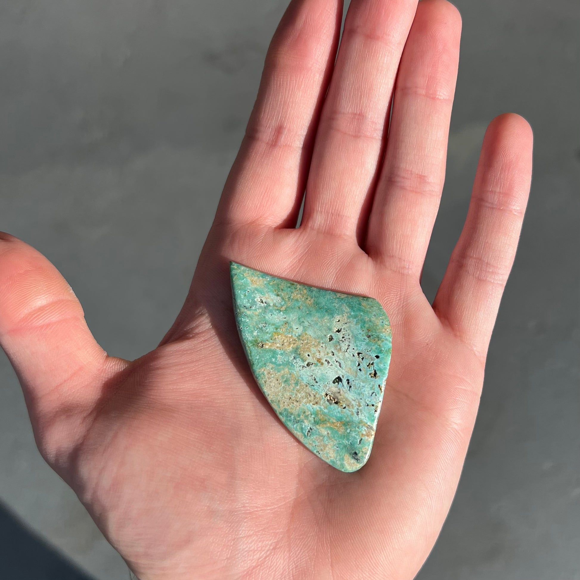 A triangular cut polished green turquoise stone from Morenci, Arizona.