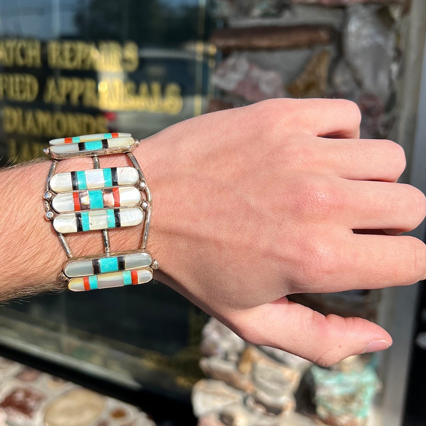 A vintage Zuni Indian-made inlay cuff bracelet set with mother of pearl, coral, turquoise, and jet stones.  The piece is signed "PONCHO."