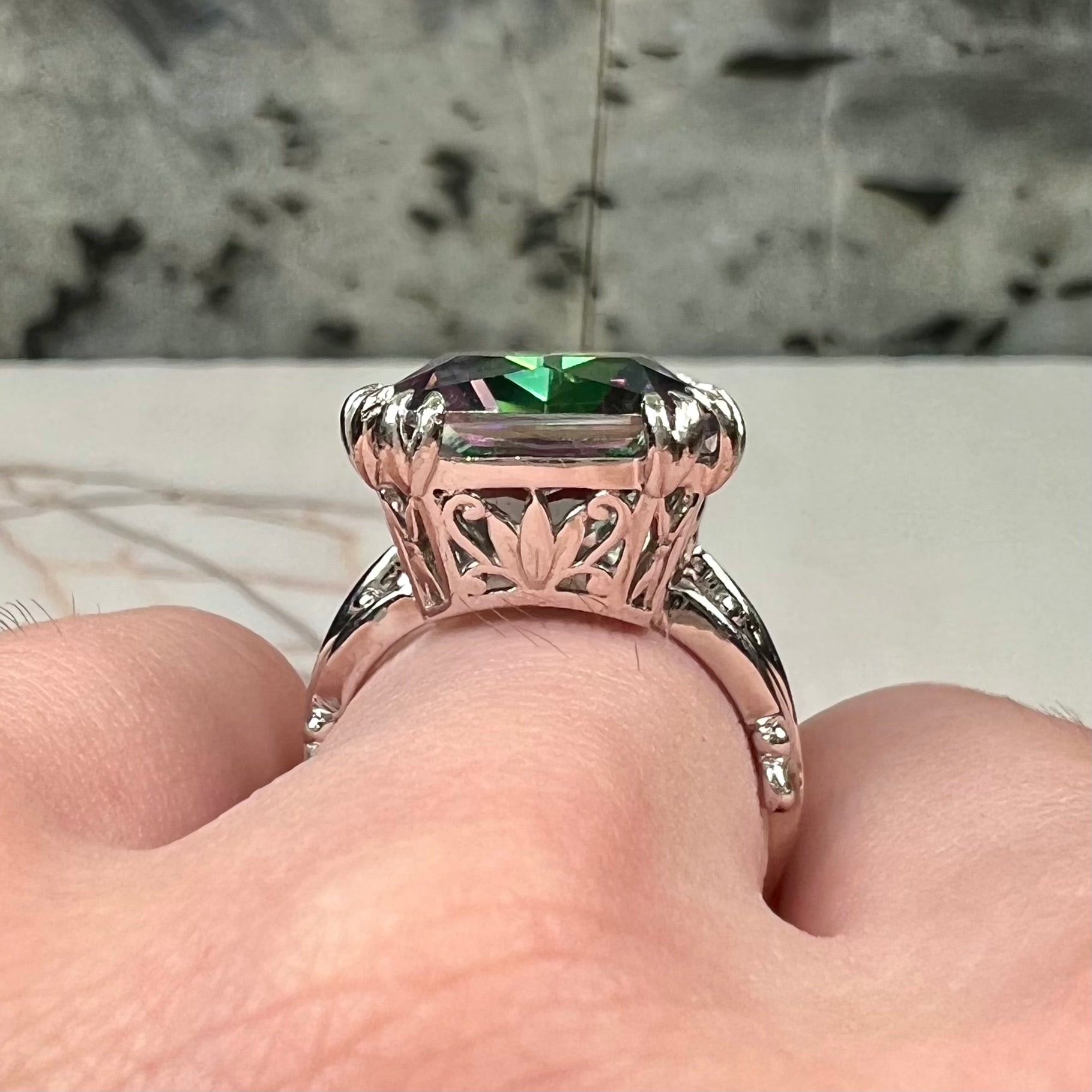 Emerald cut mystic topaz prong set in a decorative sterling silver ring.