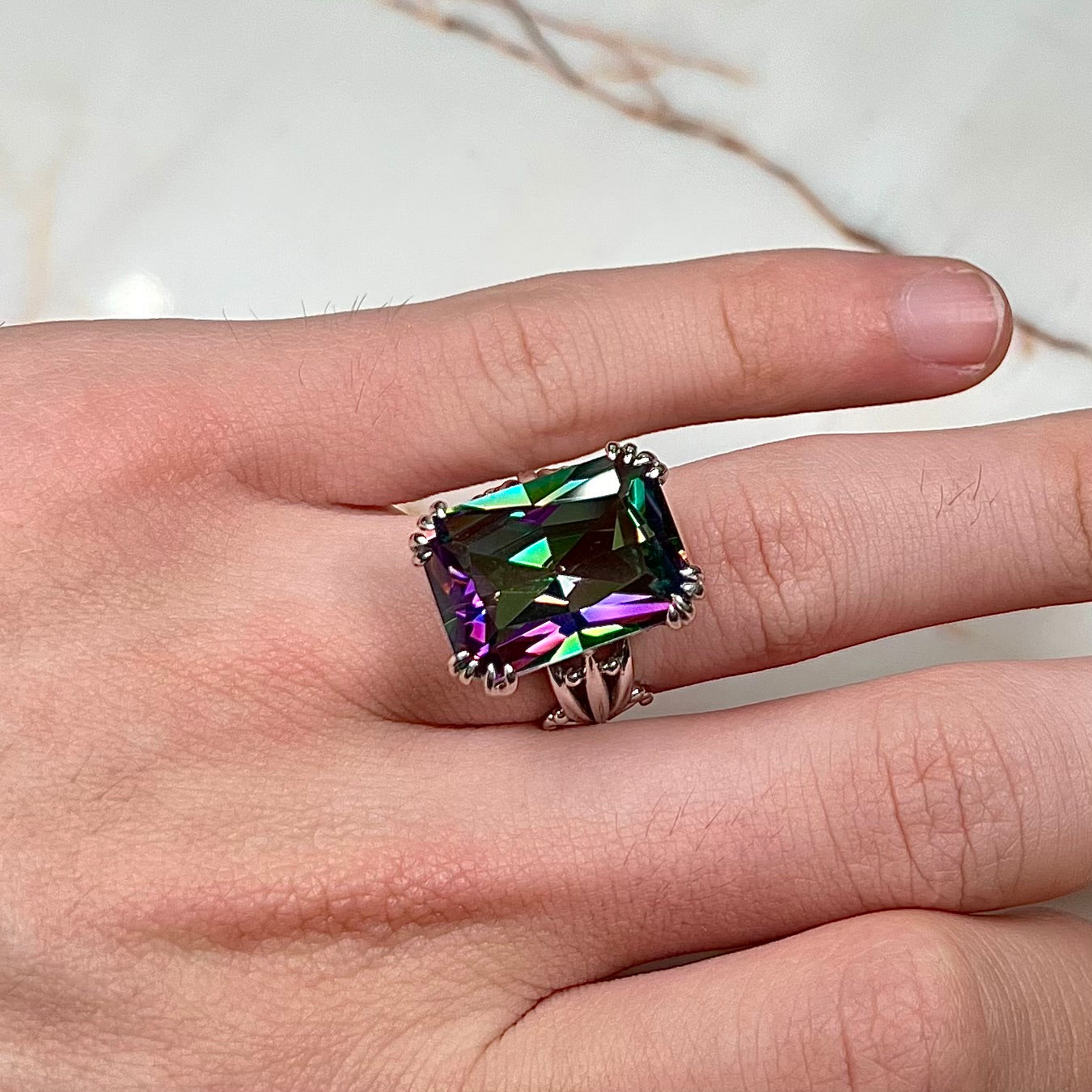 Emerald cut mystic topaz prong set in a decorative sterling silver ring.