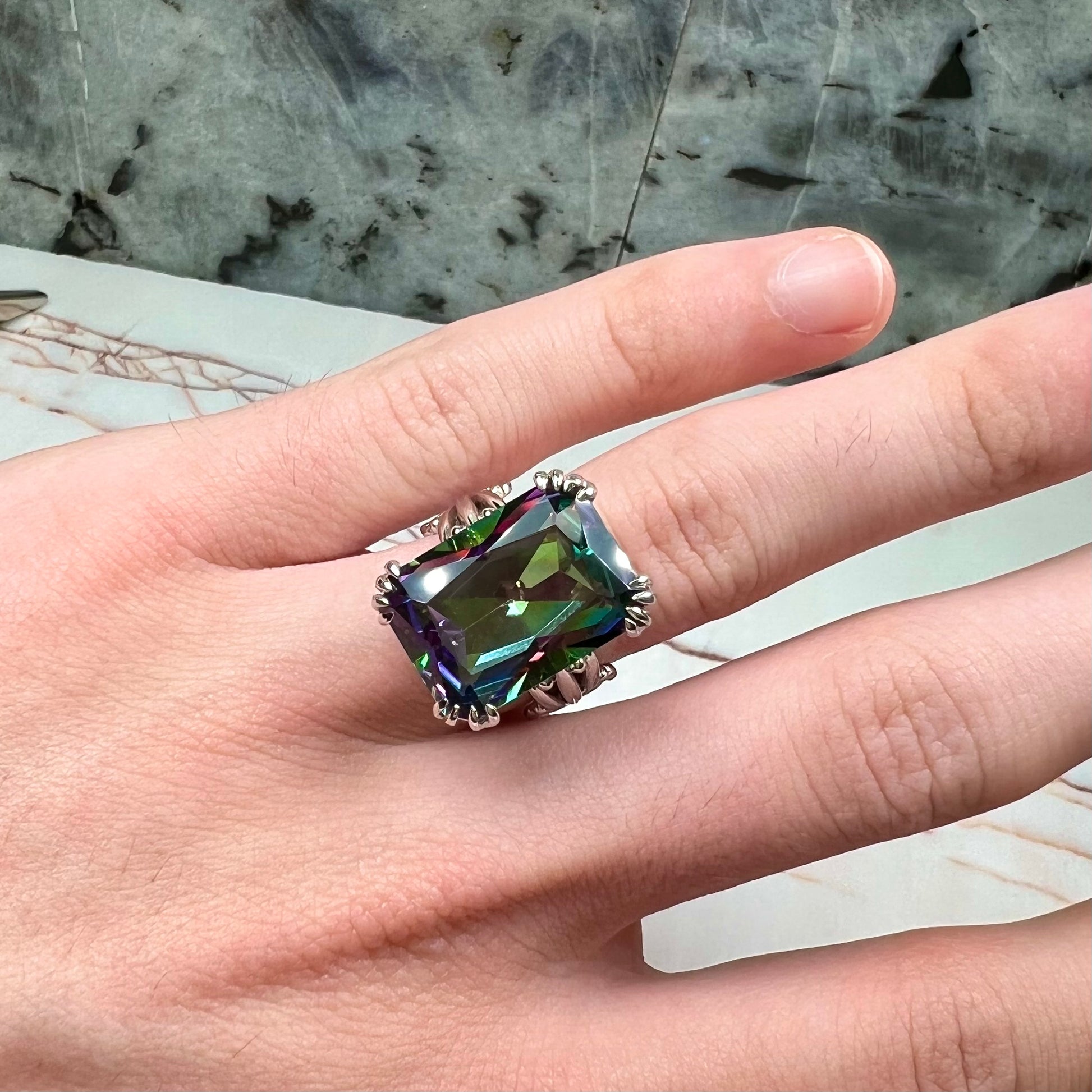 Emerald cut mystic topaz prong set in a decorative sterling silver ring.